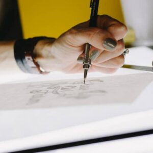 person lettering on tracing paper using mechanical pencil
